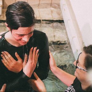 young person getting baptised in water