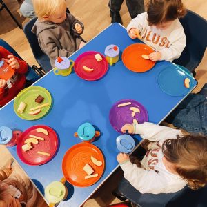 toddlers sitting around a small table eating snacks